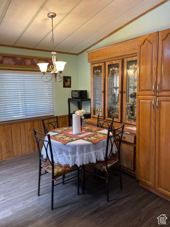 Dining area with a textured ceiling, lofted ceiling, hardwood / wood-style floors, and a chandelier