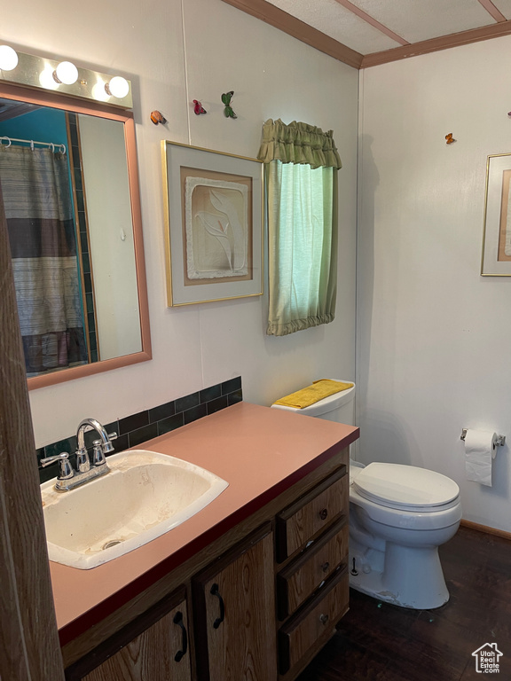 Bathroom with hardwood / wood-style flooring, crown molding, vanity, and toilet