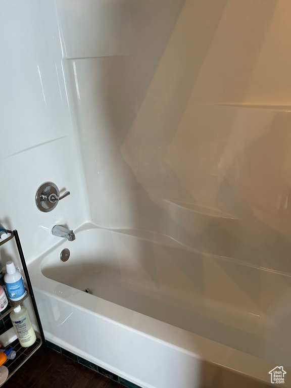 Bathroom with washtub / shower combination and hardwood / wood-style flooring