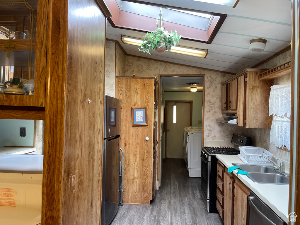 Kitchen featuring light hardwood / wood-style floors, sink, range with gas cooktop, washer and dryer, and stainless steel fridge