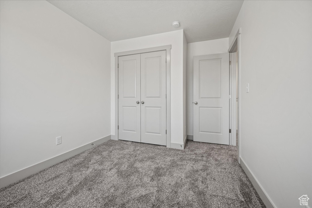 Unfurnished bedroom with light carpet and a closet