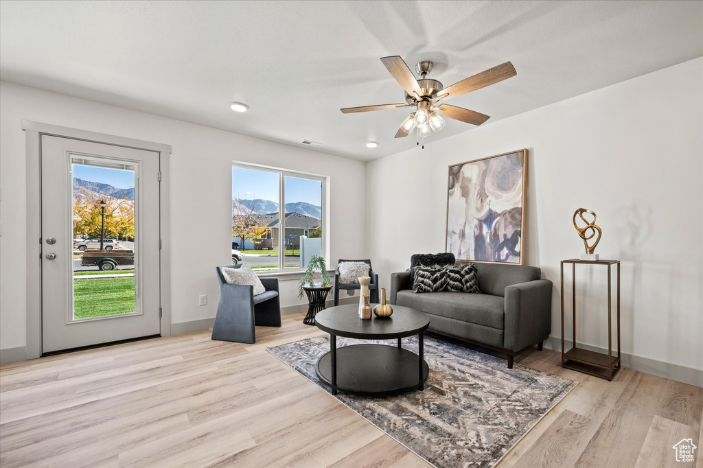 Living room featuring a mountain view, light wood-type flooring, and ceiling fan