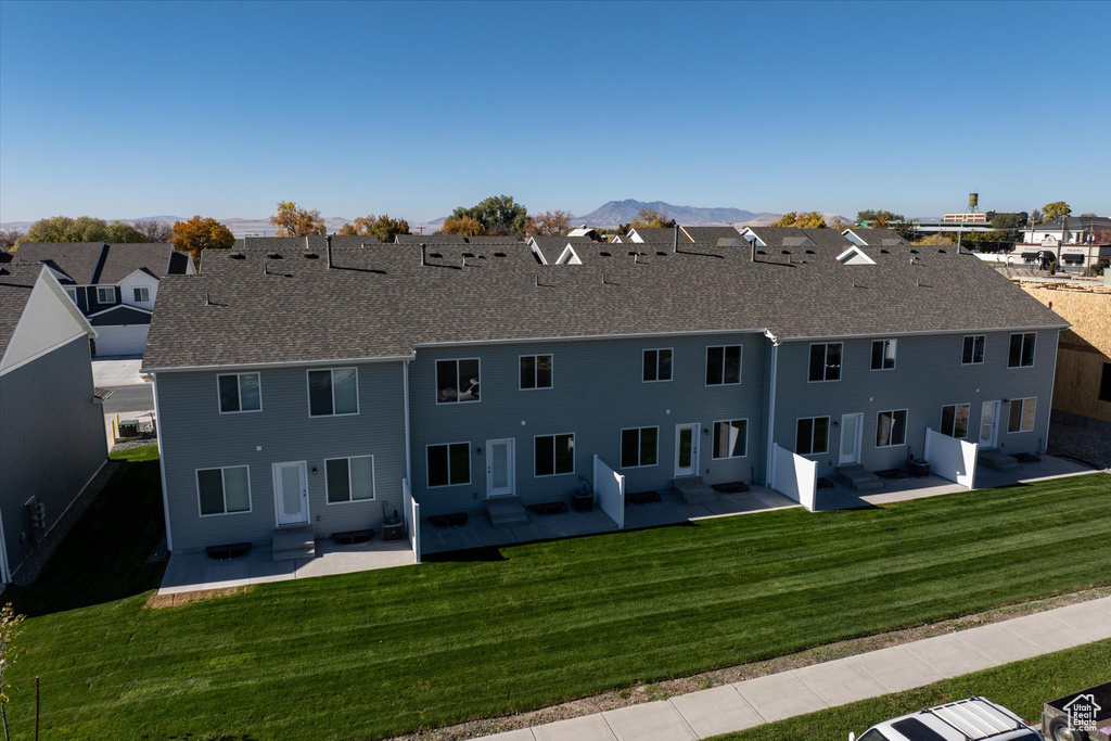 Back of property with a patio area, a lawn, and a mountain view