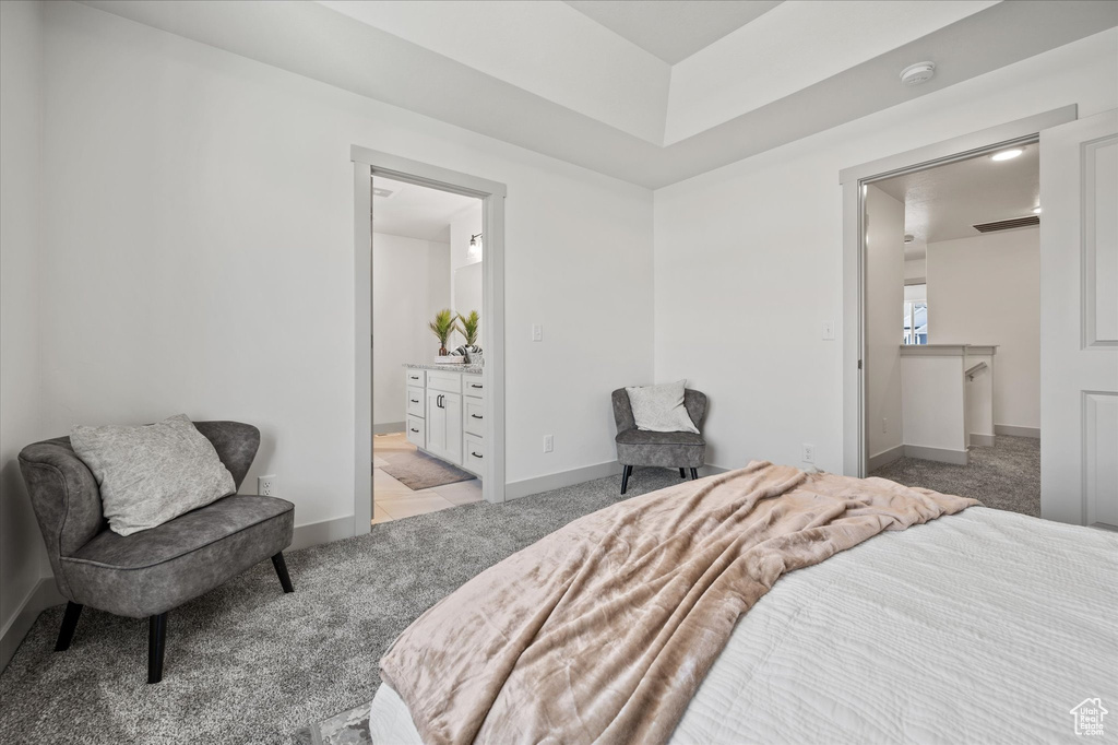 Carpeted bedroom featuring ensuite bathroom and a walk in closet
