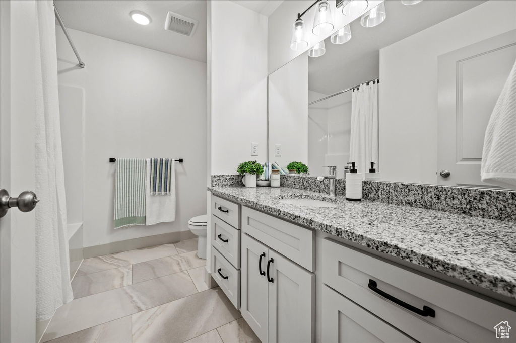 Full bathroom with shower / bath combo with shower curtain, vanity, and toilet