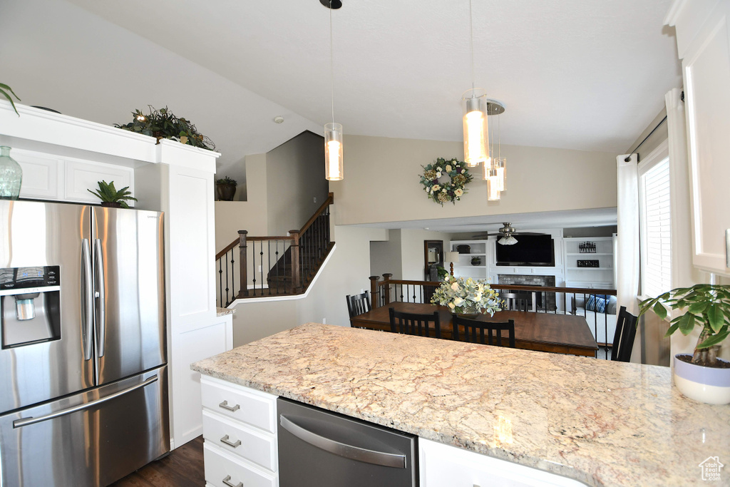 Kitchen with dark wood-type flooring, light stone counters, white cabinetry, stainless steel appliances, and lofted ceiling