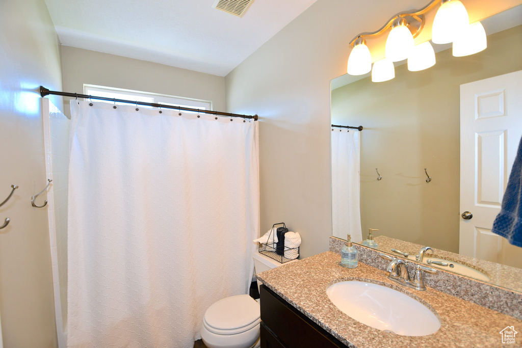 Bathroom with toilet, vanity, and walk in shower