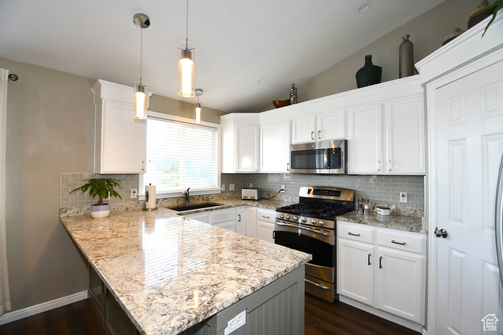 Kitchen with tasteful backsplash, vaulted ceiling, appliances with stainless steel finishes, white cabinetry, and sink