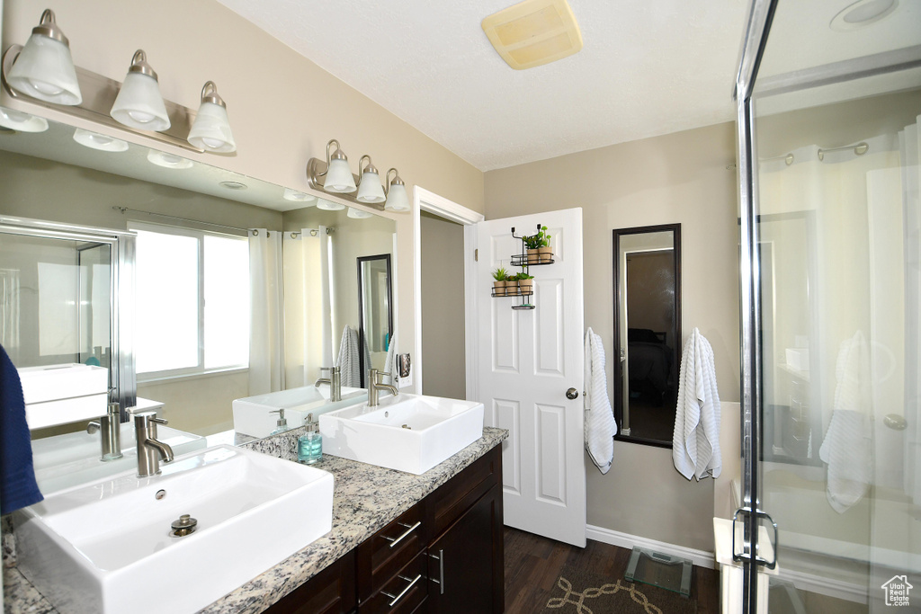 Bathroom featuring a shower with door, hardwood / wood-style floors, and vanity