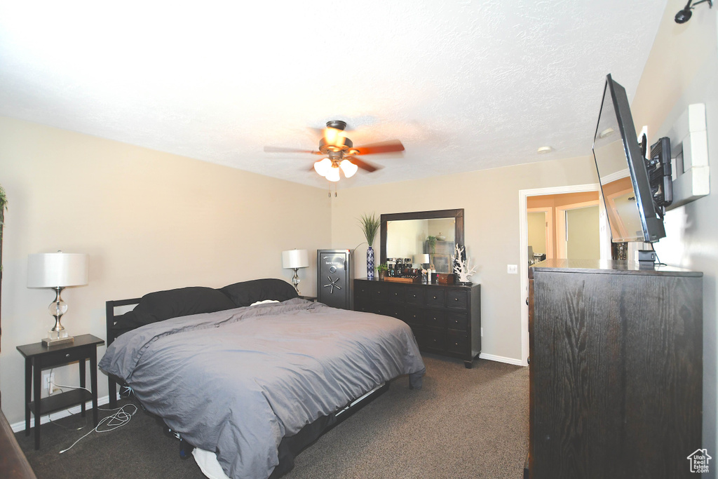 Carpeted bedroom with ceiling fan and a textured ceiling