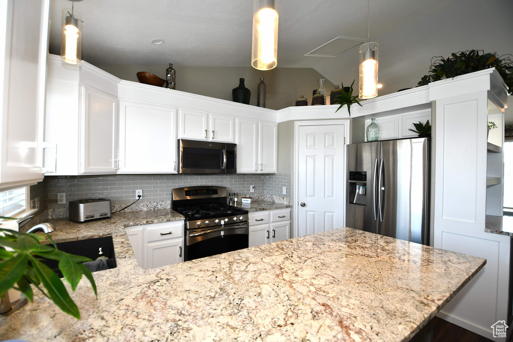 Kitchen featuring backsplash, pendant lighting, white cabinets, lofted ceiling, and stainless steel appliances