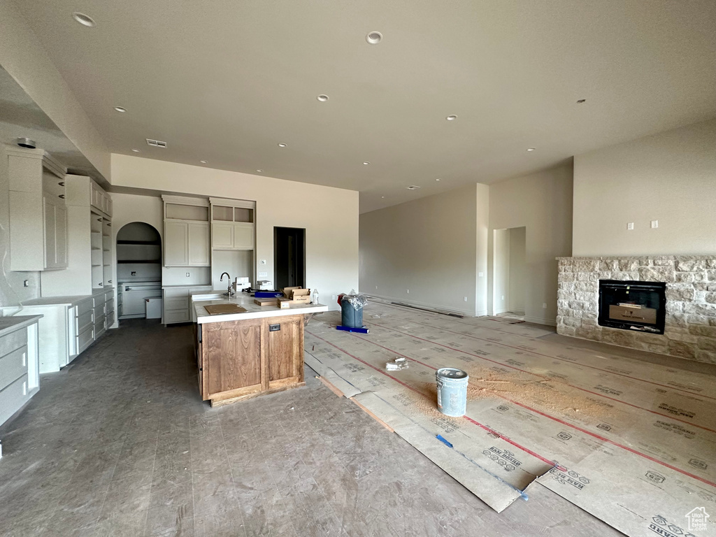 Kitchen featuring a large island with sink, sink, and a stone fireplace