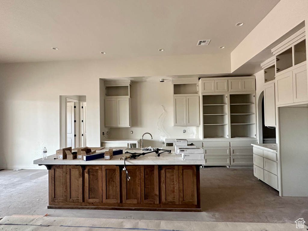 Kitchen with a large island with sink, concrete flooring, and a breakfast bar area