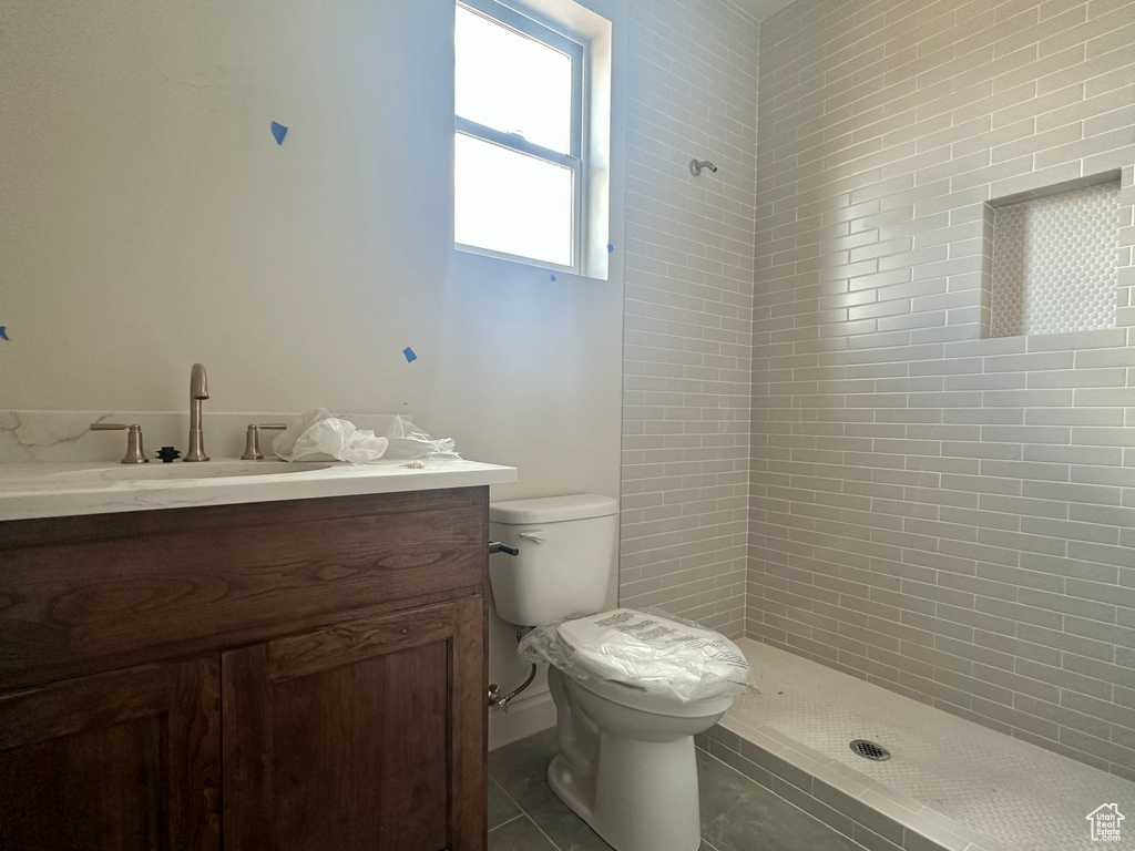 Bathroom featuring toilet, vanity, a tile shower, and tile patterned floors