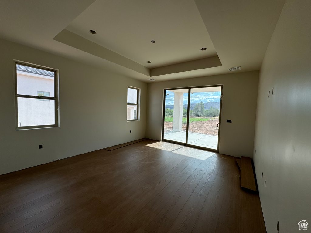 Unfurnished room with a raised ceiling, plenty of natural light, and hardwood / wood-style floors