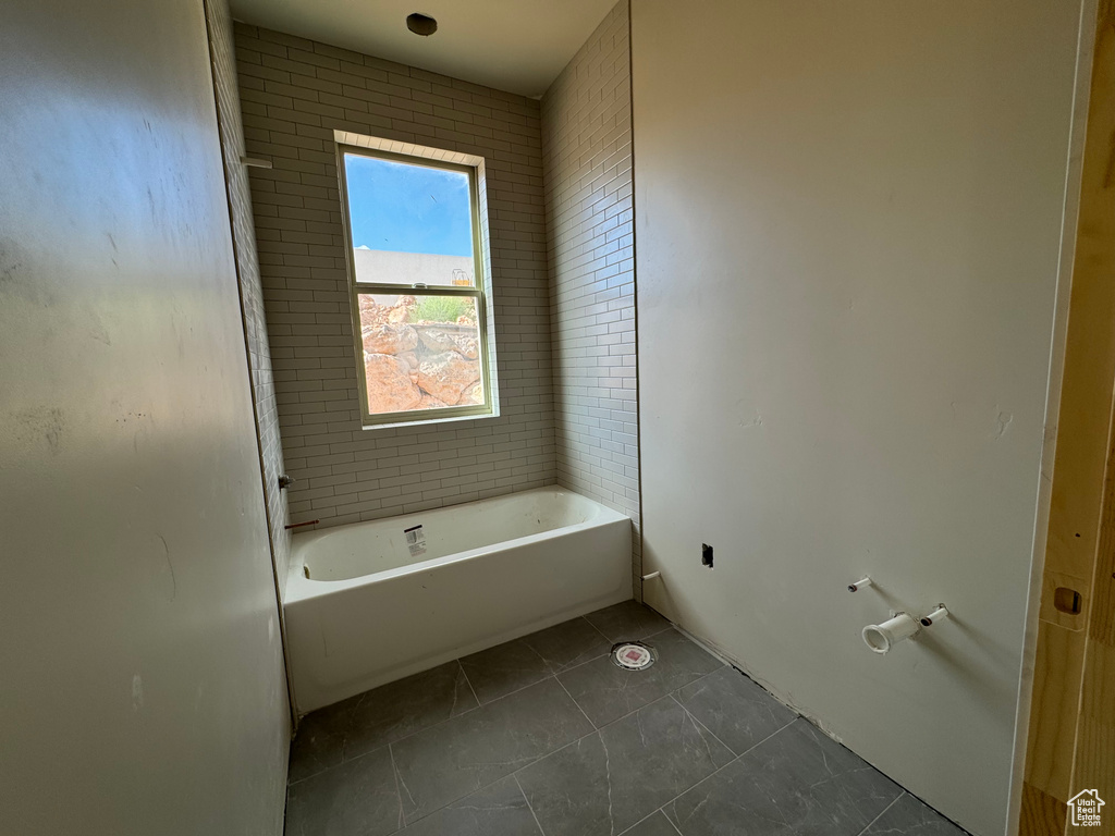 Bathroom with a washtub and tile patterned flooring