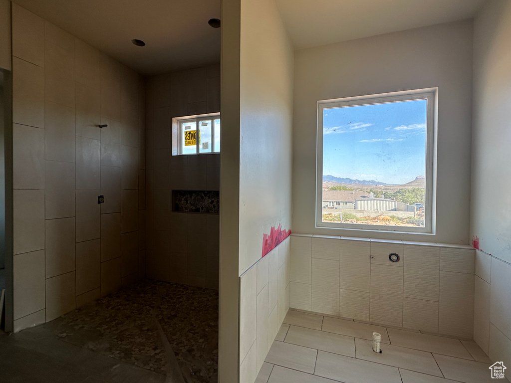 Bathroom with a mountain view, tile walls, tile patterned flooring, and a tile shower