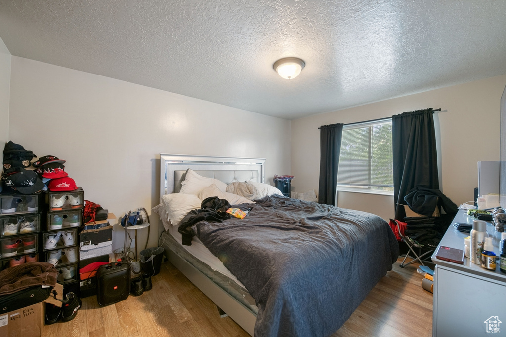 Bedroom with a textured ceiling and light hardwood / wood-style flooring