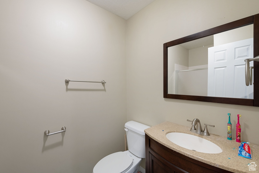 Bathroom with toilet, vanity, and a shower with shower door