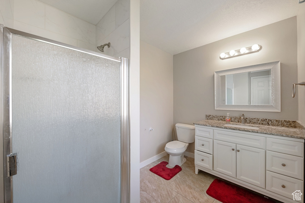 Bathroom featuring tile patterned floors, vanity, walk in shower, and toilet