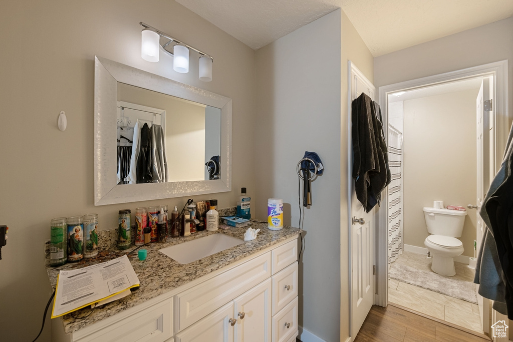 Bathroom with hardwood / wood-style floors, toilet, and vanity