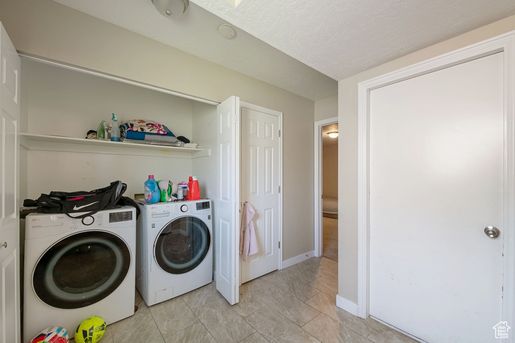 Clothes washing area featuring independent washer and dryer and light tile patterned floors