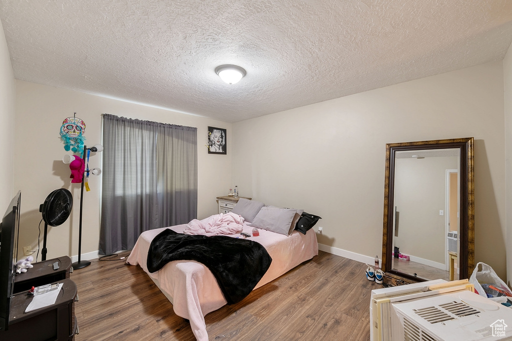 Bedroom with a textured ceiling and hardwood / wood-style floors