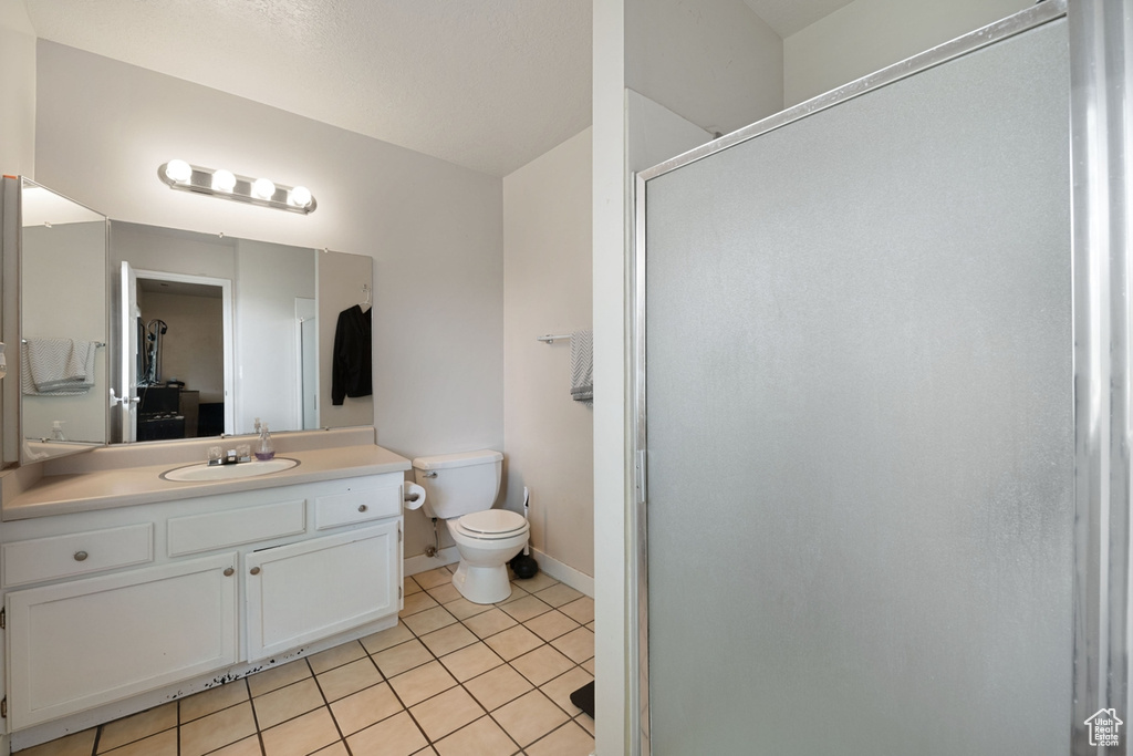 Bathroom featuring tile patterned flooring, an enclosed shower, vanity, and toilet