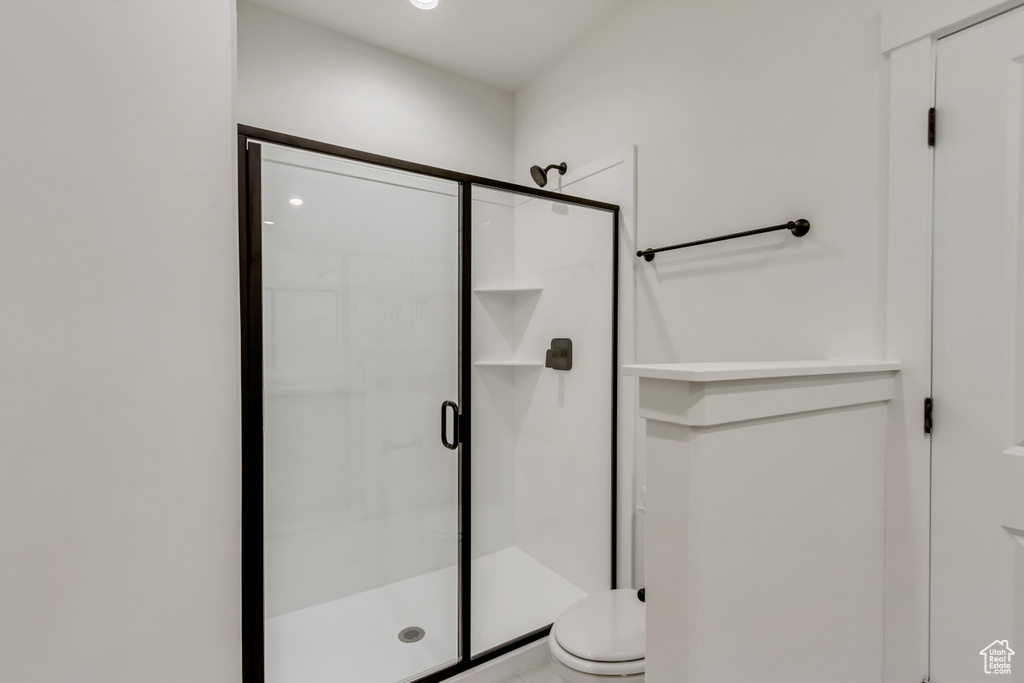 Bathroom featuring a shower with door and toilet