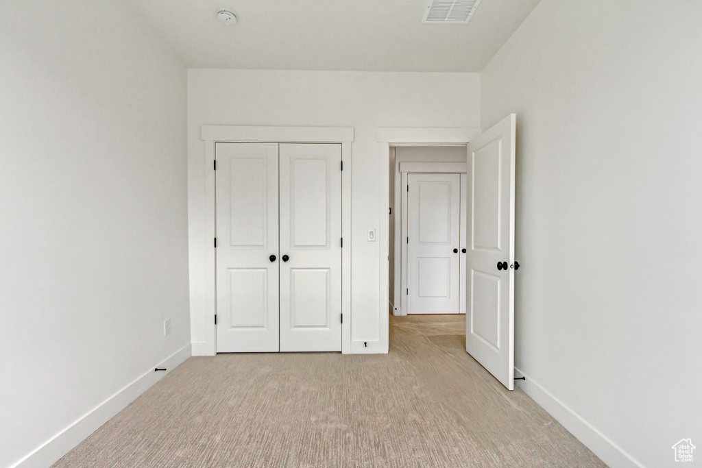 Unfurnished bedroom featuring a closet and light carpet