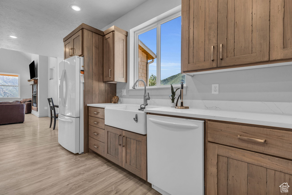 Kitchen featuring light hardwood / wood-style floors, a wealth of natural light, sink, and white appliances