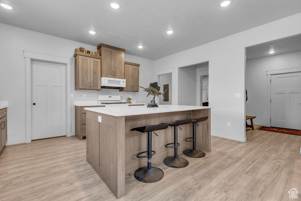 Kitchen featuring a breakfast bar area, light hardwood / wood-style flooring, range, and a center island