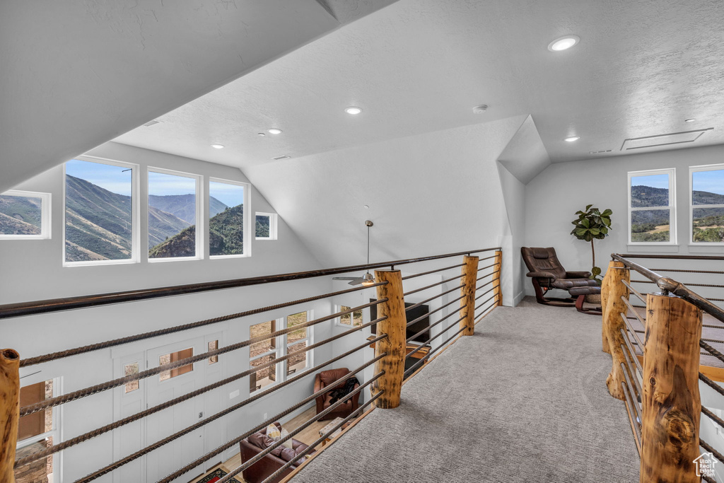 Corridor with a mountain view, light colored carpet, a textured ceiling, and lofted ceiling