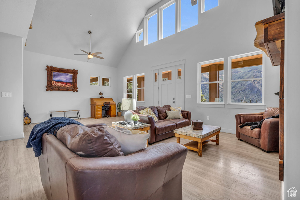 Living room featuring light wood-type flooring, high vaulted ceiling, and a healthy amount of sunlight