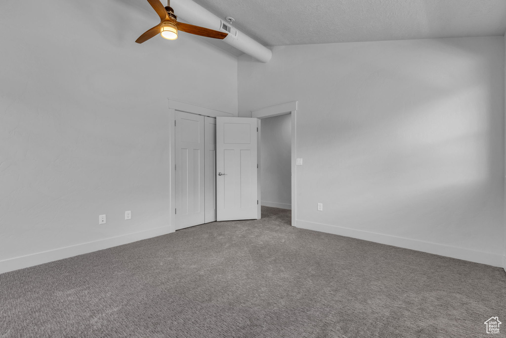 Unfurnished bedroom featuring carpet floors, ceiling fan, and lofted ceiling with beams