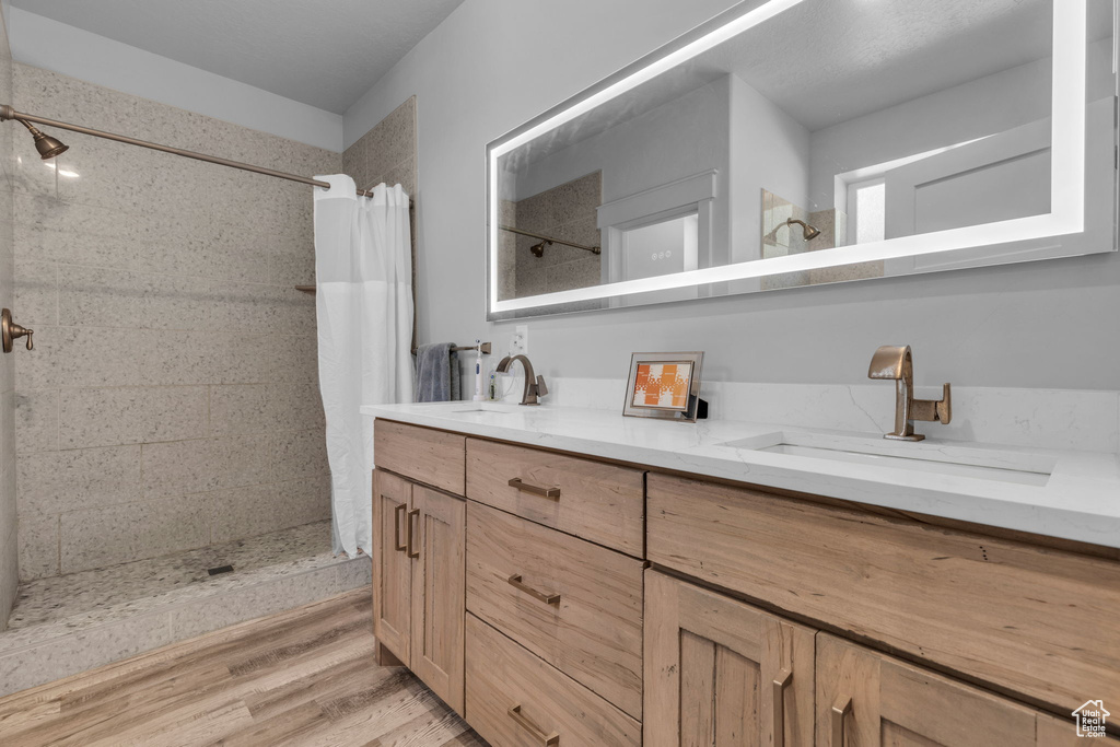 Bathroom featuring hardwood / wood-style flooring, curtained shower, and vanity