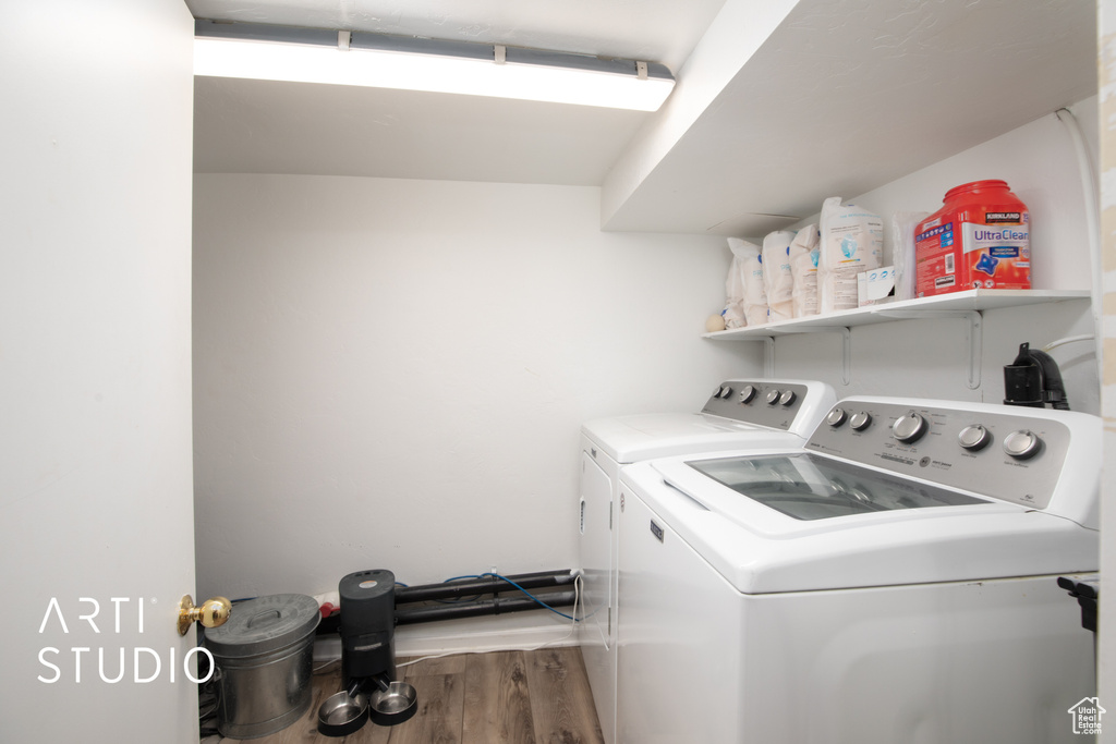 Clothes washing area with dark hardwood / wood-style floors and washing machine and clothes dryer