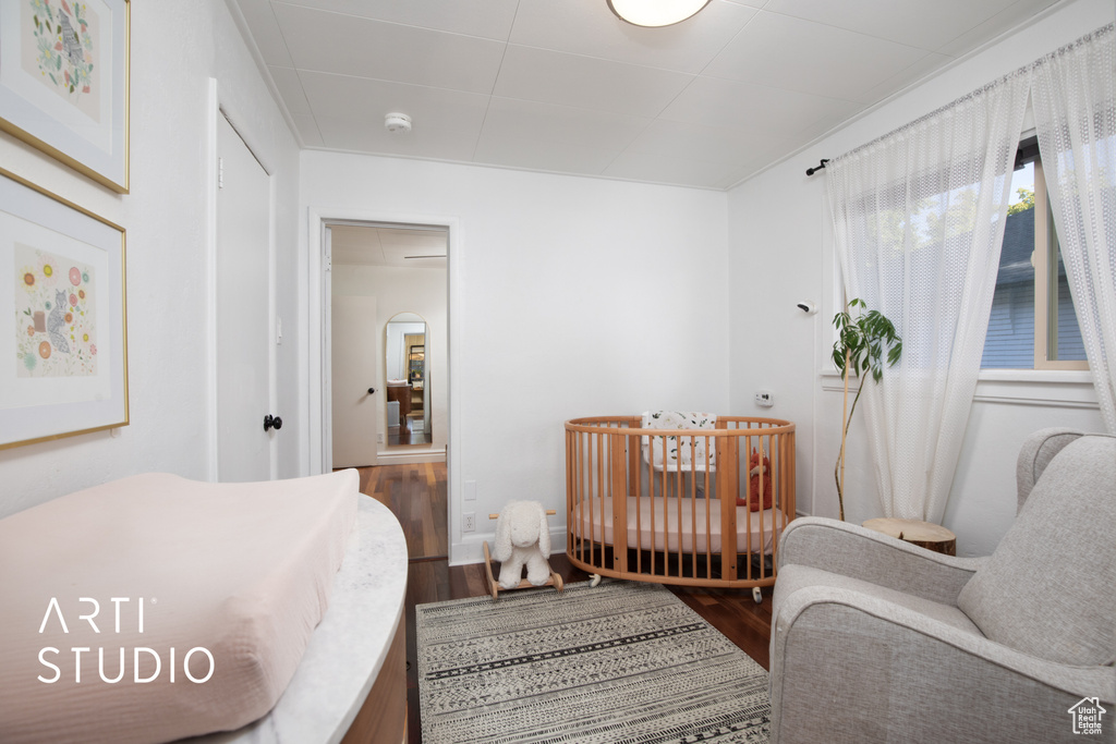 Bedroom with a nursery area and wood-type flooring