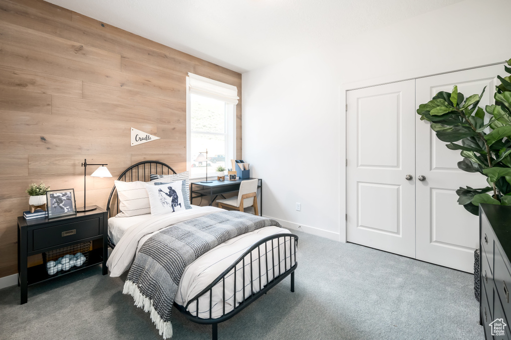 Bedroom with a closet, wooden walls, and carpet flooring