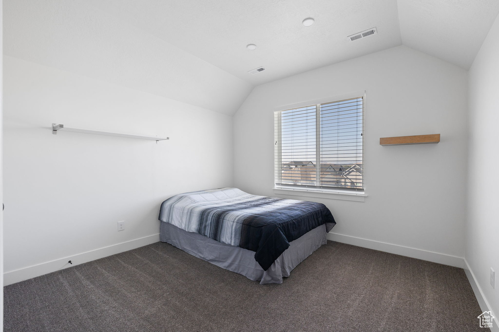 Carpeted bedroom featuring vaulted ceiling