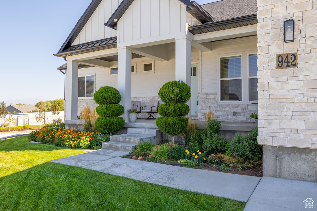 Doorway to property featuring a yard and covered porch