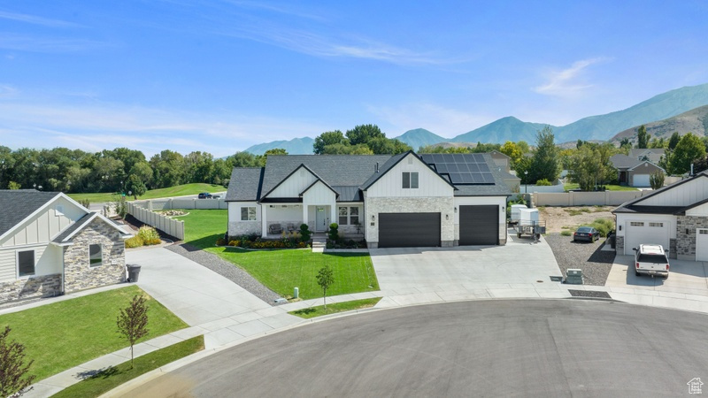 Modern farmhouse style home with solar panels, a garage, a front lawn, and a mountain view