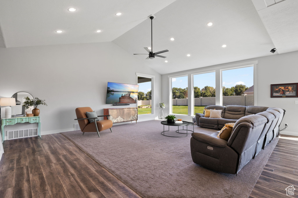 Living room with dark wood-type flooring, ceiling fan, and high vaulted ceiling