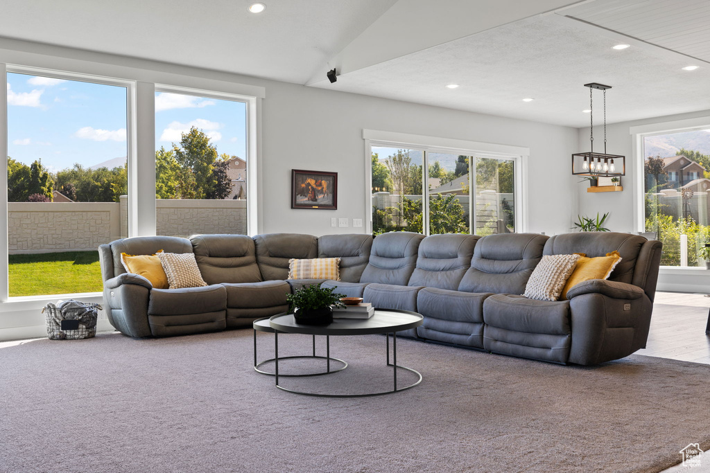 Carpeted living room featuring vaulted ceiling and an inviting chandelier