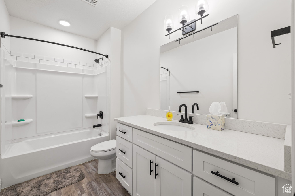 Full bathroom with vanity, toilet, tub / shower combination, and hardwood / wood-style flooring