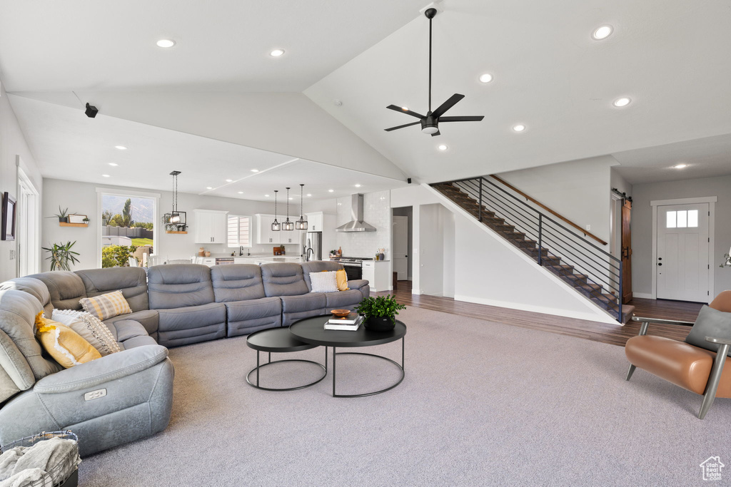 Living room with high vaulted ceiling, ceiling fan, and light wood-type flooring