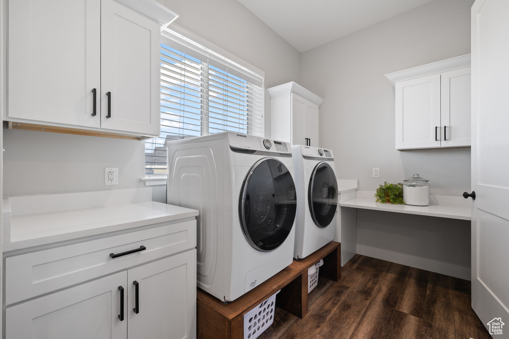 Laundry area with washing machine and clothes dryer, cabinets, and dark hardwood / wood-style floors