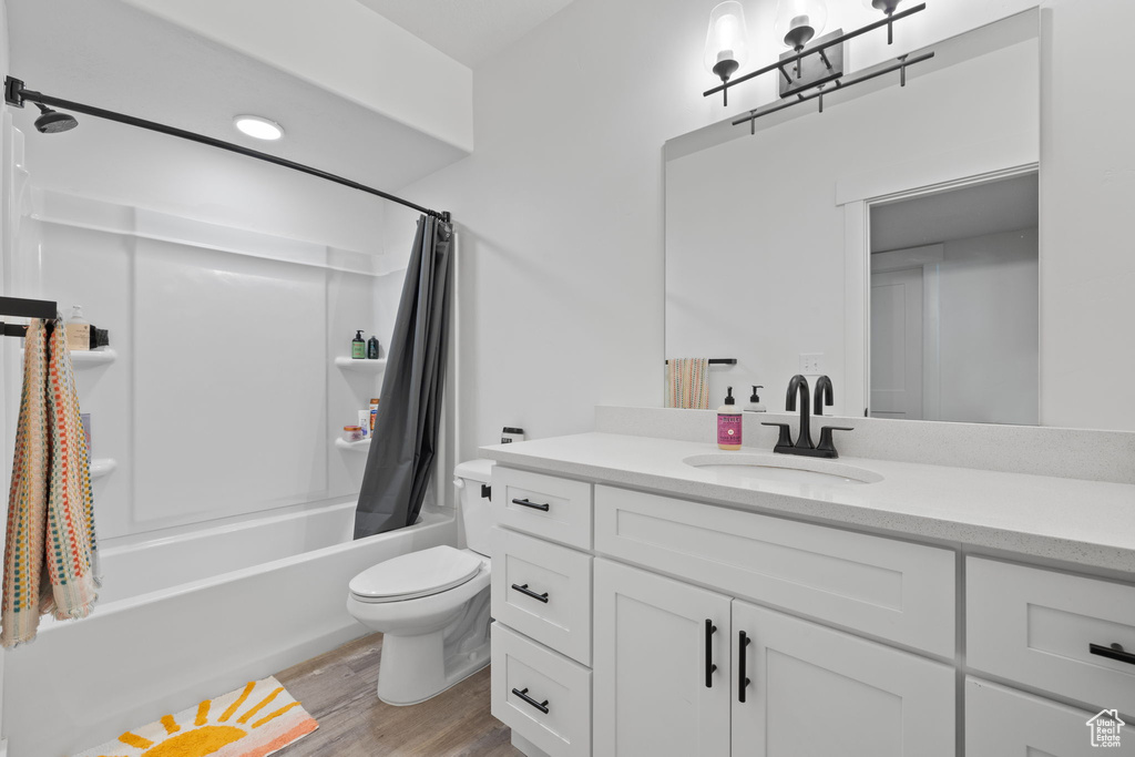 Full bathroom featuring vanity, toilet, hardwood / wood-style floors, and shower / bath combo