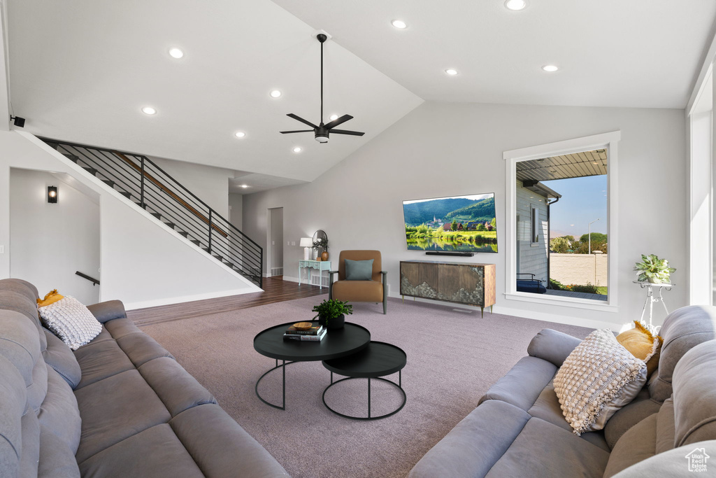 Carpeted living room with high vaulted ceiling, ceiling fan, and a fireplace