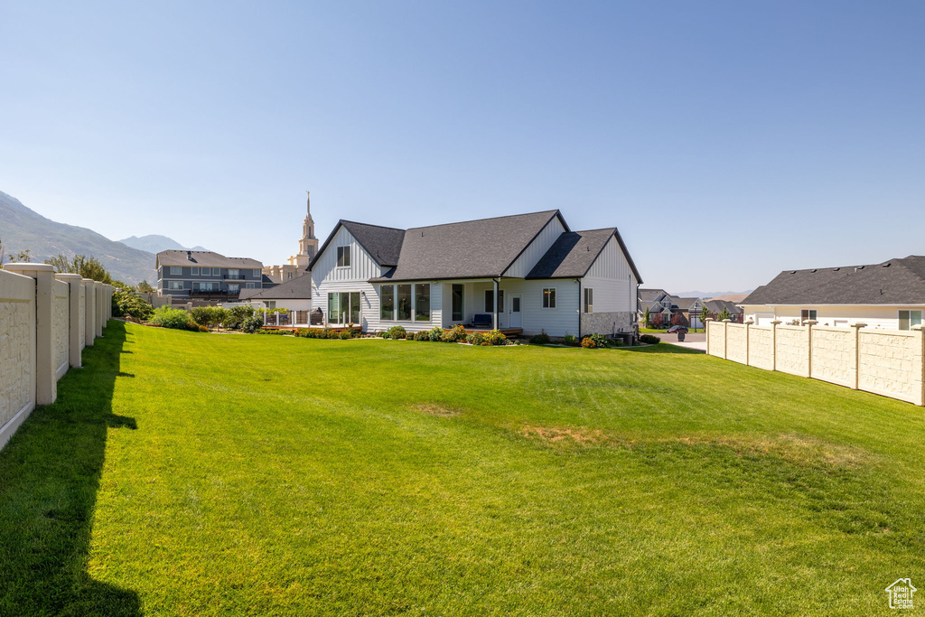 Rear view of house with a mountain view and a lawn